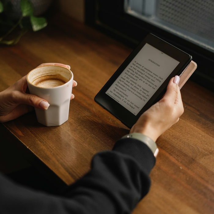 a person sitting at a table with a tablet and a cup of coffee